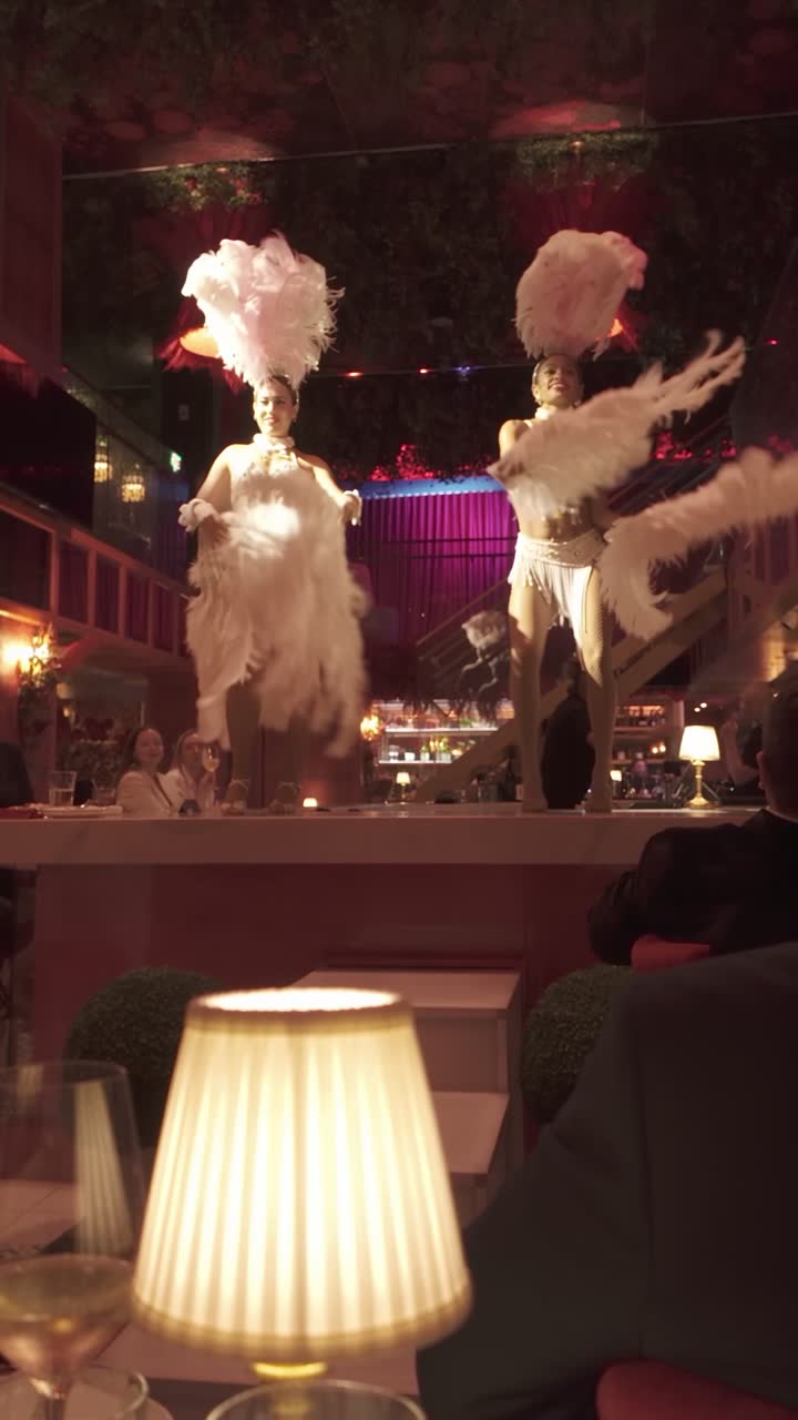 Feather-fan dancers beside a table at J'Adore
